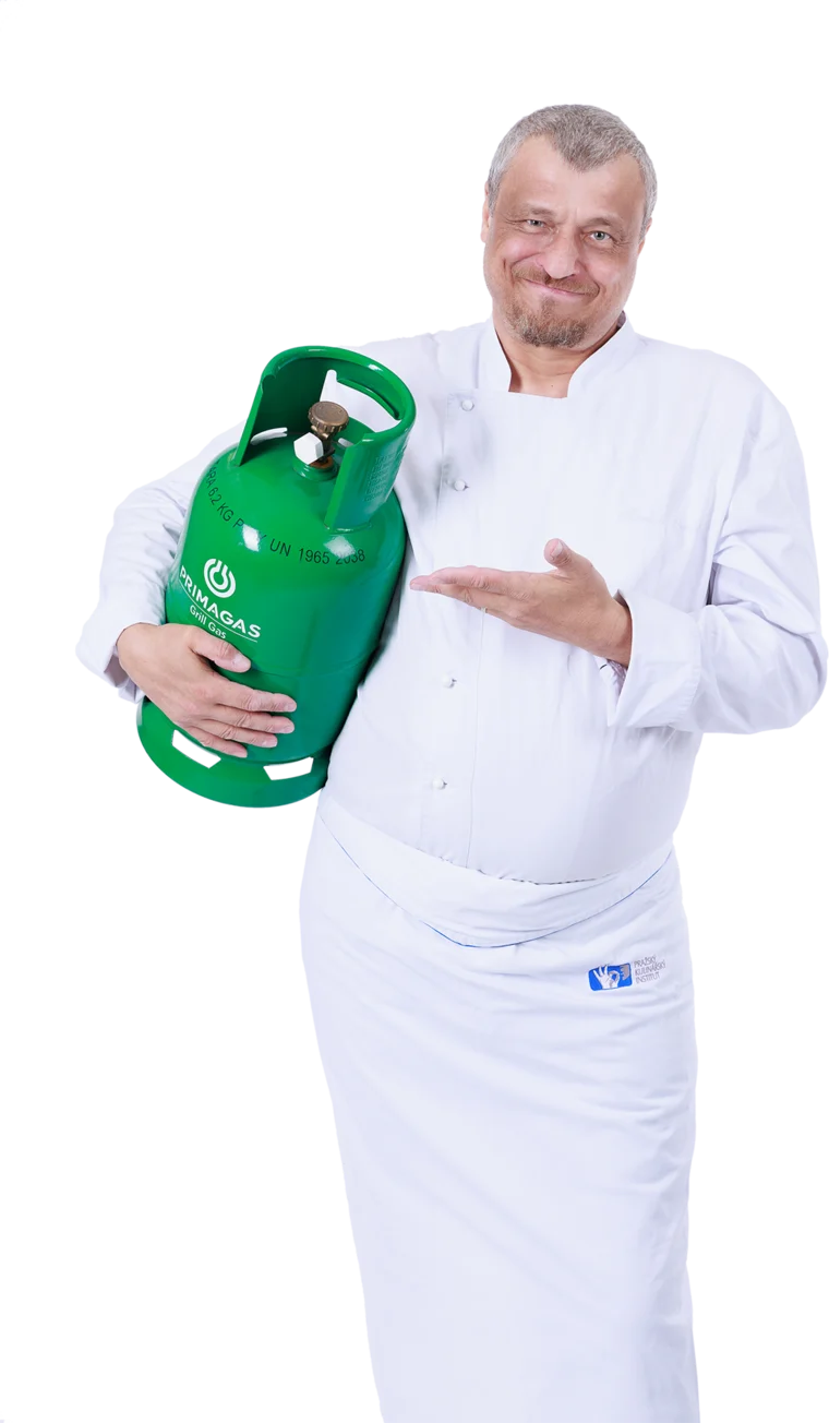 Kuchař drží zelenou plynovou láhev Primagas a ukazuje na ni.